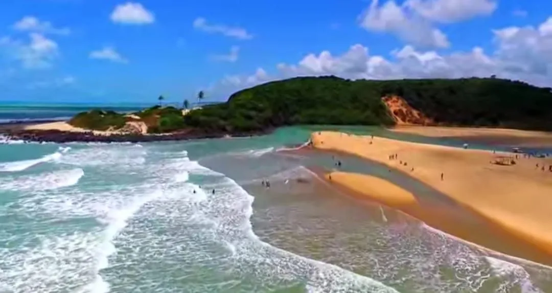 A foz do Camaratuba vista do alto, com o banco de areia e o morro que fecha o canto da praia.