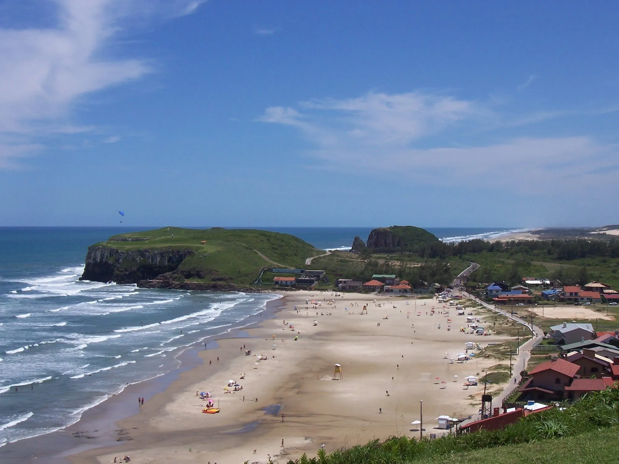 A enseada da Praia da Cal vista do alto, fechada à esquerda pelo morro da Guarita e pela Torre, com a orla de Torres à direita.