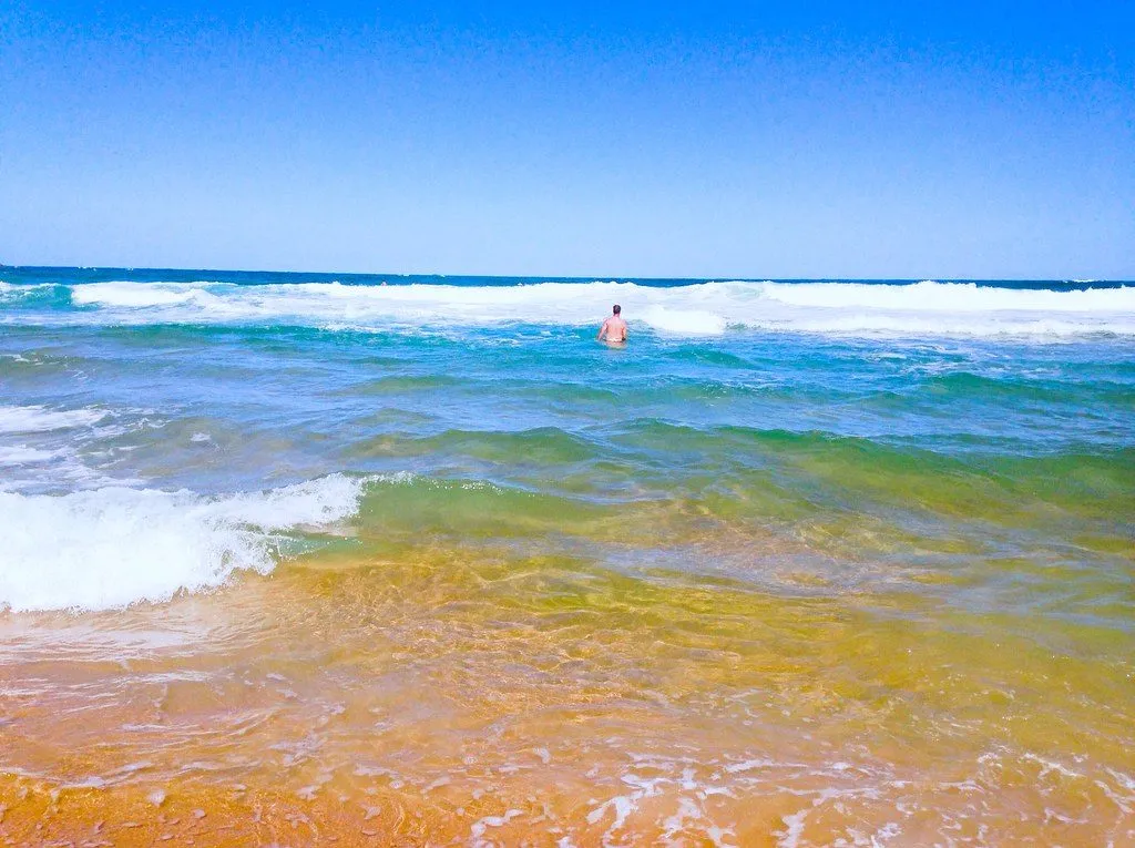 A arrebentação da Silveira quebrando perto da areia, na faixa curta que concentra os bancos e a fila.